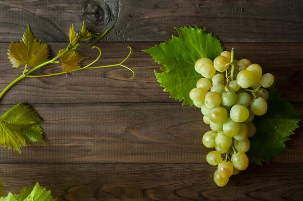 Grappolo di uva verde con foglie sullo sfondo di legno — Foto Stock