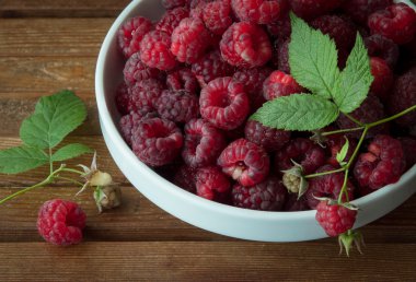 ahşap masa üzerinde beyaz kase kokulu olgun ahududu