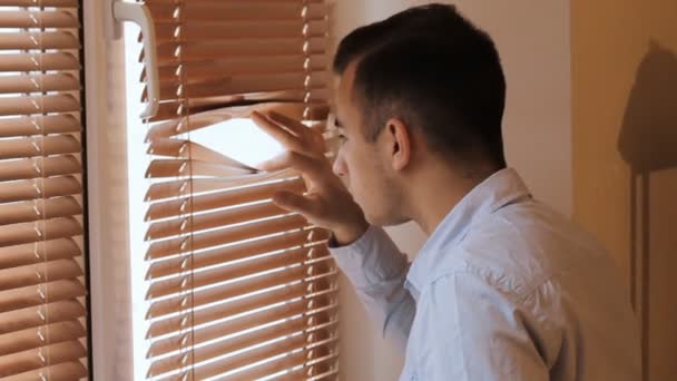 Joven empresario espiando a través de las persianas de la ventana — Vídeos de Stock