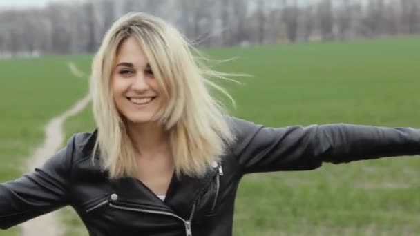 Retrato de una joven rockera sonriendo y mirando a la cámara en el campo verde — Vídeos de Stock