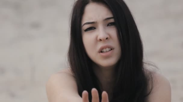 Jolie brune assise à la plage et contorse des émotions 