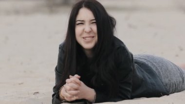 Şirin esmer yalanlar üzerine kum ve gülümsüyor