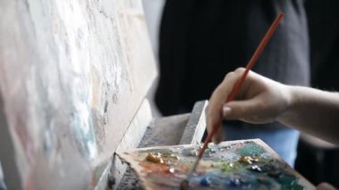 Sanatçı fırça boya palete bir şövale üzerinde koyar