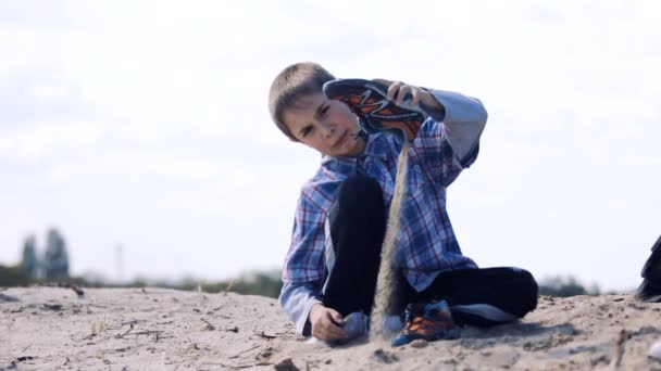 Barnet häller sand ur hans skor — Stockvideo