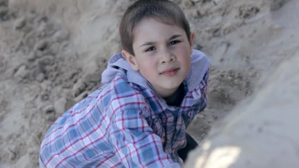 砂の採石場の格子縞のシャツを着た小さな男の子の肖像画 — ストック動画