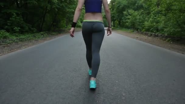Menina andando na estrada na floresta. fitness ao ar livre. tiro com steadicam — Vídeo de Stock