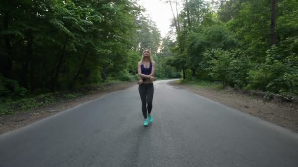 A mulher vai para a estrada na floresta. fitness ao ar livre. tiro com steadicam — Vídeo de Stock