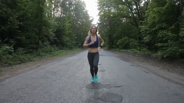 Mujer corredora corriendo por la carretera en el bosque. fitness al aire libre. inyectado con steadicam — Vídeos de Stock