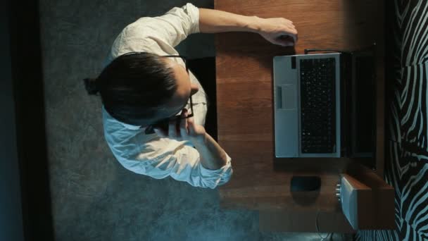 Uomo che lavora ad un computer portatile parlando al telefono — Video Stock