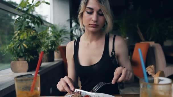 Blond tjej i restaurangen äter sallad — Stockvideo