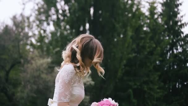 Porträt einer hübschen Frau im weißen Kleid wirft Blumen — Stockvideo