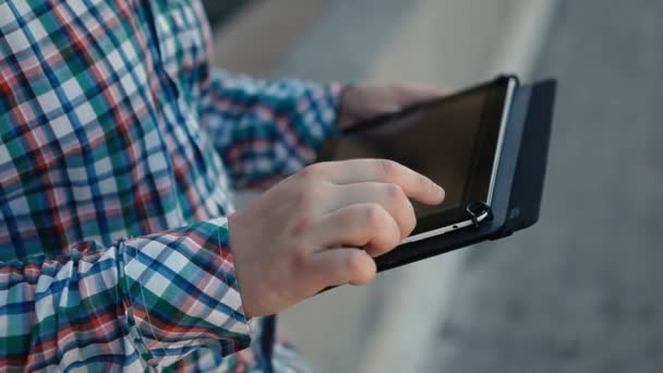 Крупный план человека в клетчатой рубашке использует планшет на открытом воздухе — стоковое видео