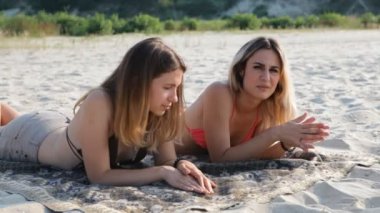 Güneşlenme ve sahilde konuşurken iki kız