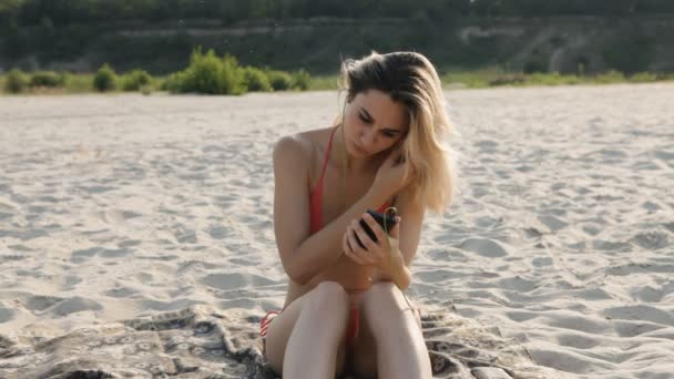 Menina ouvindo música em fones de ouvido e usando smartphone na praia — Vídeo de Stock