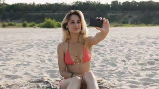 Sexig tjej i rosa bikini gör selfie på stranden — Stockvideo