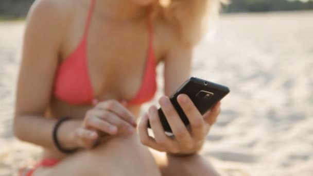 Detailní záběr sexy žena pomocí smartphone na pláži — Stock video