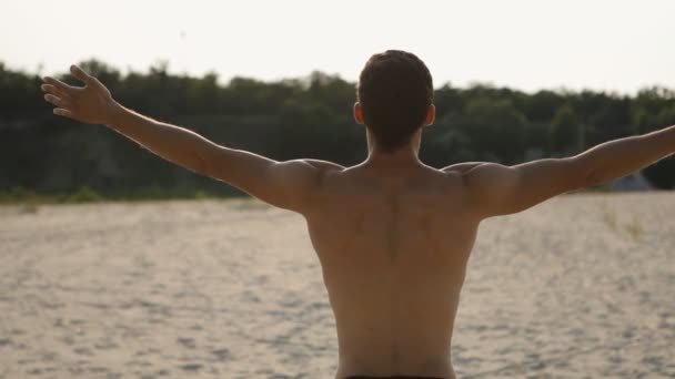 Chico deportivo medita en la playa — Vídeos de Stock