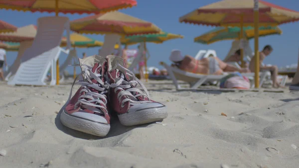 Sahilde kırmızı spor ayakkabılar, tatilcilerin arka plan insanlar.