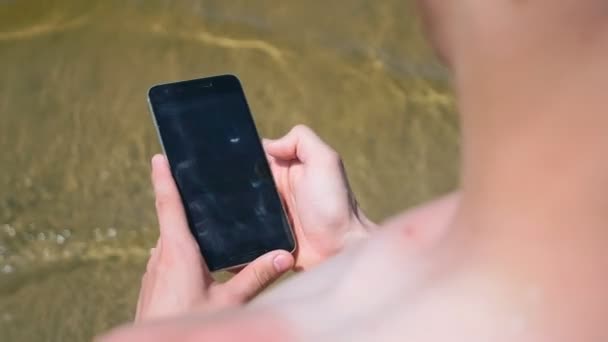 Gros plan de l'homme utilisant son téléphone intelligent à la plage — Video