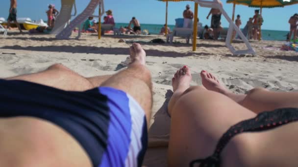 Пара засмагає на пляжі, вид від першої особи — стокове відео