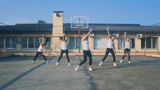 Dívky v bílých tričkách tančí na hřišti v létě — Stock video