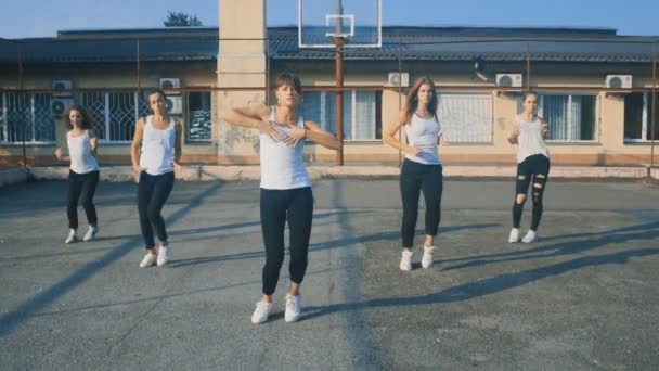 Девушки в белых футболках танцуют на детской площадке в замедленной съемке — стоковое видео