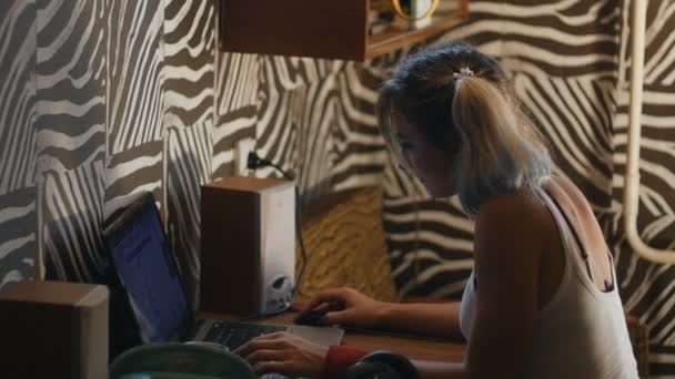 Дівчина-підліток у своїй кімнаті працює ноутбук — стокове відео