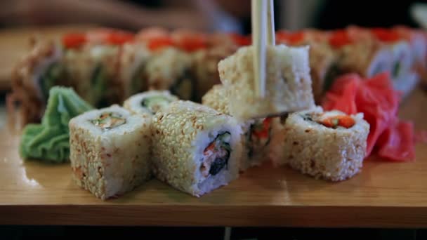 Primer plano de sushi en un restaurante japonés. Hombre con palillos tomando sushi — Vídeo de stock