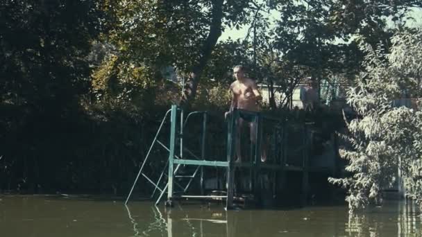 Человек, прыгающий в озеро. Парень прыгает в пруд спереди — стоковое видео