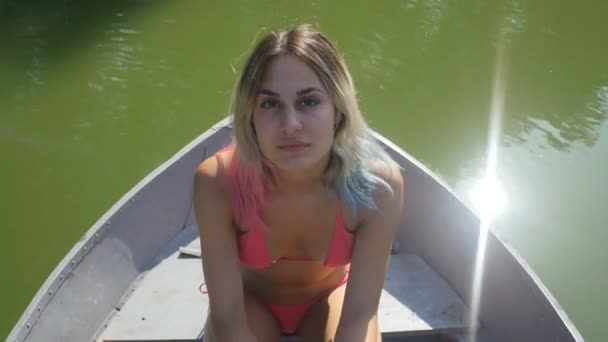 Chica en traje de baño rosa flotando en un barco en el lago — Vídeo de stock