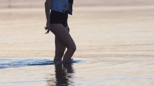 Zeitlupe: Verspielte Frau spielt bei Sonnenuntergang mit Meerwasser — Stockvideo
