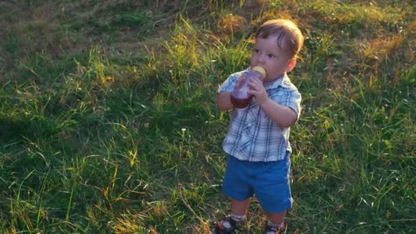 Retrato de menino bebendo suco de uma mamadeira em câmera lenta — Vídeo de Stock