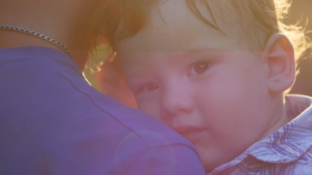 Close-up of a father holding his young son in his arms at sunset in slow motion — Stock Video