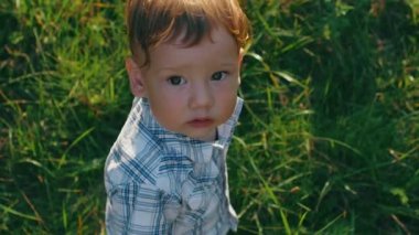 bebek çocuk portresi yakından kameraya yeşil çim zemin üzerine görünüyor.