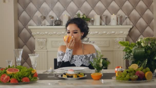 Женщина, сидящая за столом с грейпфрутом в руках — стоковое видео