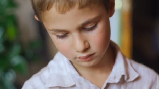 Portret van een schattige jongen met grote ogen naar beneden te kijken — Stockvideo