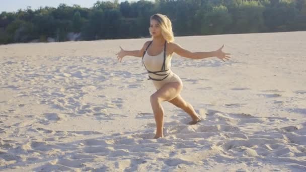 Woman professional dancer meditating on the sand at sunset in slow motion — Stock Video