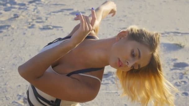 Retrato de una mujer rubia haciendo yoga en la playa al atardecer — Vídeo de stock