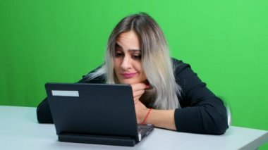 masada oturan ve bir dizüstü bilgisayar çalışan kız. Yeşil ekran stüdyo
