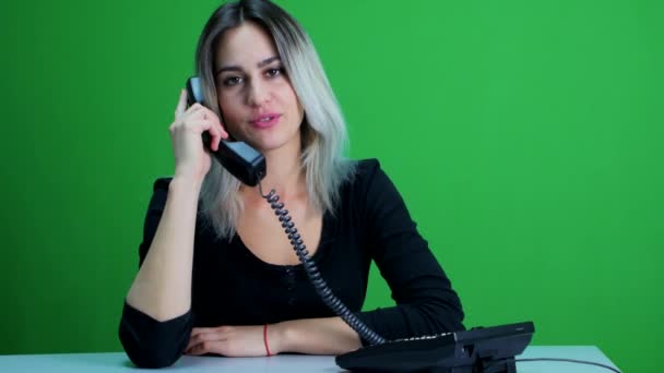 Uma rapariga gira num escritório a falar ao telefone com um cliente. Estúdio tela verde — Vídeo de Stock