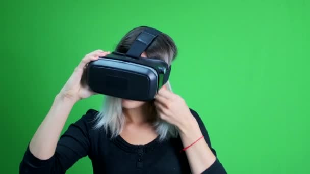 Mujer joven se puso la cabeza de realidad virtual en una pantalla verde . — Vídeos de Stock