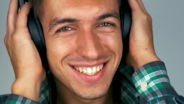 Primer plano del hombre sonríe y escucha música en los auriculares — Vídeos de Stock