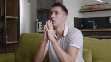 Üzgün adam sorun için yardım istiyor, Tanrı 'ya dua ediyor. Dindar erkek evdeki kanepede oturup dua eder. Umutla dua eden adam.