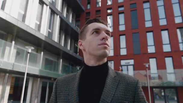Πορτρέτο του στοχαστικού επιχειρηματία φορώντας κοστούμι κοιτάζοντας έξω, ενώ στέκεται κοντά στο σύγχρονο κτίριο γραφείων. Νέοι άνδρες επιχειρηματίας κοιτάζοντας γύρω στο κέντρο της πόλης — Αρχείο Βίντεο