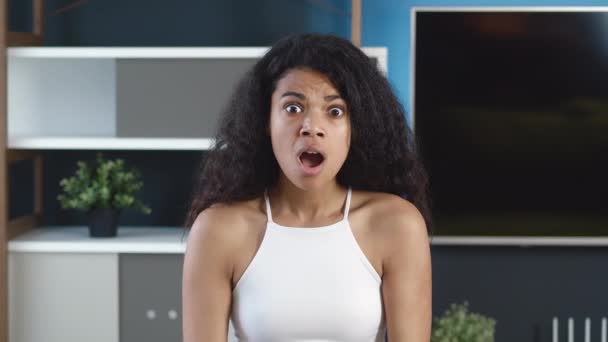 ショックを受けたアフリカの混合人種の若い女性は、自宅のオフィスの背景でカメラを見てストレスを感じる. — ストック動画