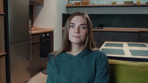 Potret wanita muda Kaukasia yang cantik melihat kamera duduk di sofa sendirian di rumah, wanita bahagia merasa puas berpose di ruang tamu — Stok Video