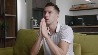 Üzgün adam sorun için yardım istiyor, Tanrı 'ya dua ediyor. Dindar erkek evdeki kanepede oturup dua eder. Umutla dua eden adam.