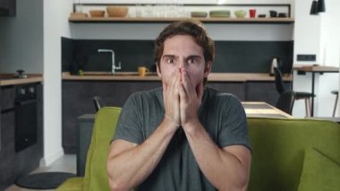 Haberlerden korkan adam oturma odasındaki kanepede kameraya bakar. Şok olmuş ve şaşırmış bir adamın portresi evdeki kanepede oturuyor. TV 'de korku filmi izliyorum..