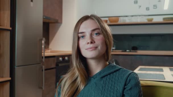 Porträtt av vackra leende ung kvinna tittar på kameran sitta på soffan ensam hemma, glad kvinna känner sig nöjd poserar i vardagsrummet — Stockvideo