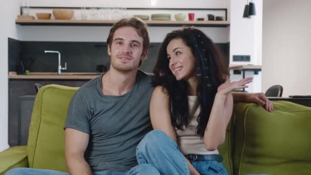 Όμορφο νεαρό ζευγάρι κάνει βιντεοκλήση στο σπίτι. Νεαρή ευτυχισμένη οικογένεια που έχει online βίντεο chat κάμερα ενώ κάθεται στον καναπέ στο σαλόνι. — Αρχείο Βίντεο